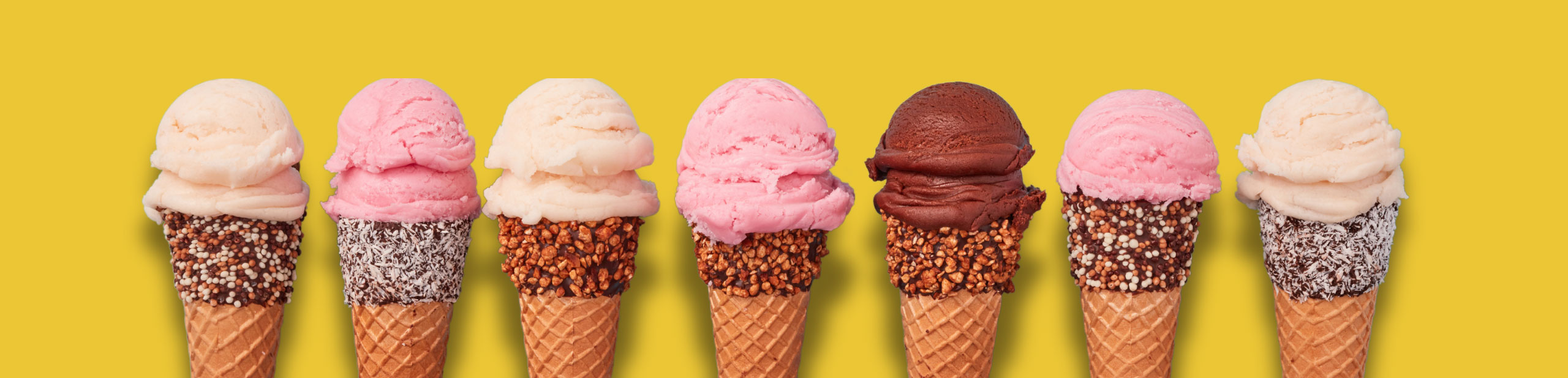 seven ice cream cones with different flavours and chocolate sprinkles