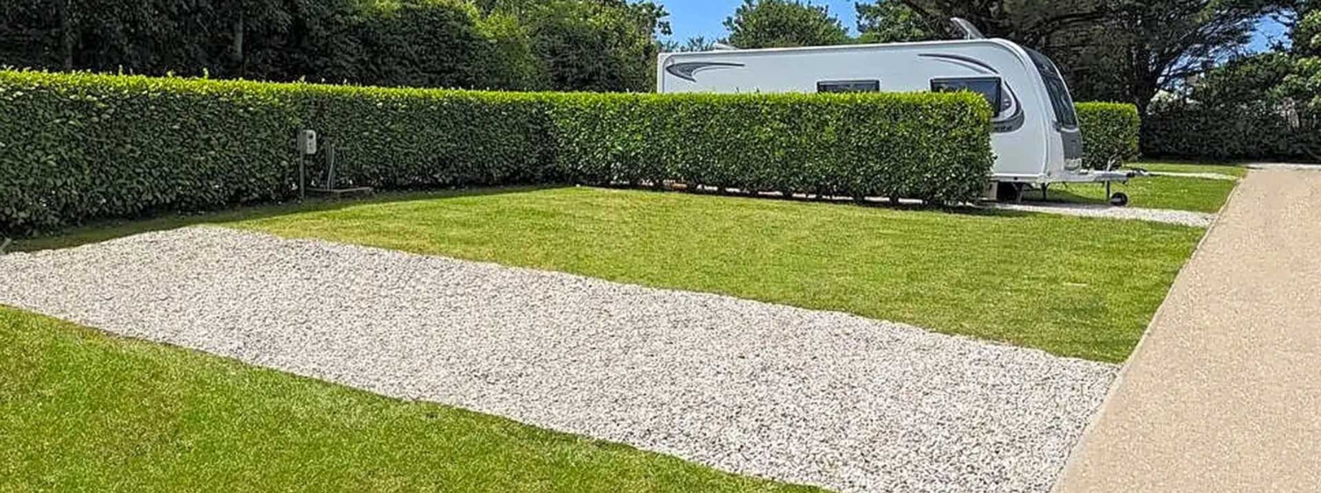 Gravel and grass pitch with hedging for privacy, perfect for caravans or camping in Cornwall.