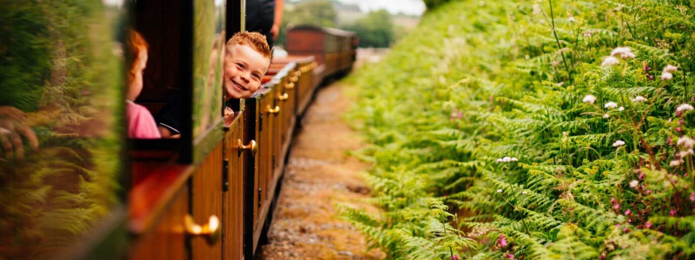 a child looking out of the lappa valley railway smiling as the train is travelling between its destinations in cornwall